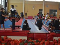 Two campers jumping into the foam pit in Gymnastics, one is mid-air, tumbling and the other is poised ready to jump
