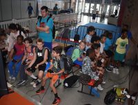summer camp attendees playing video games while seated together on benches with an adult looking on